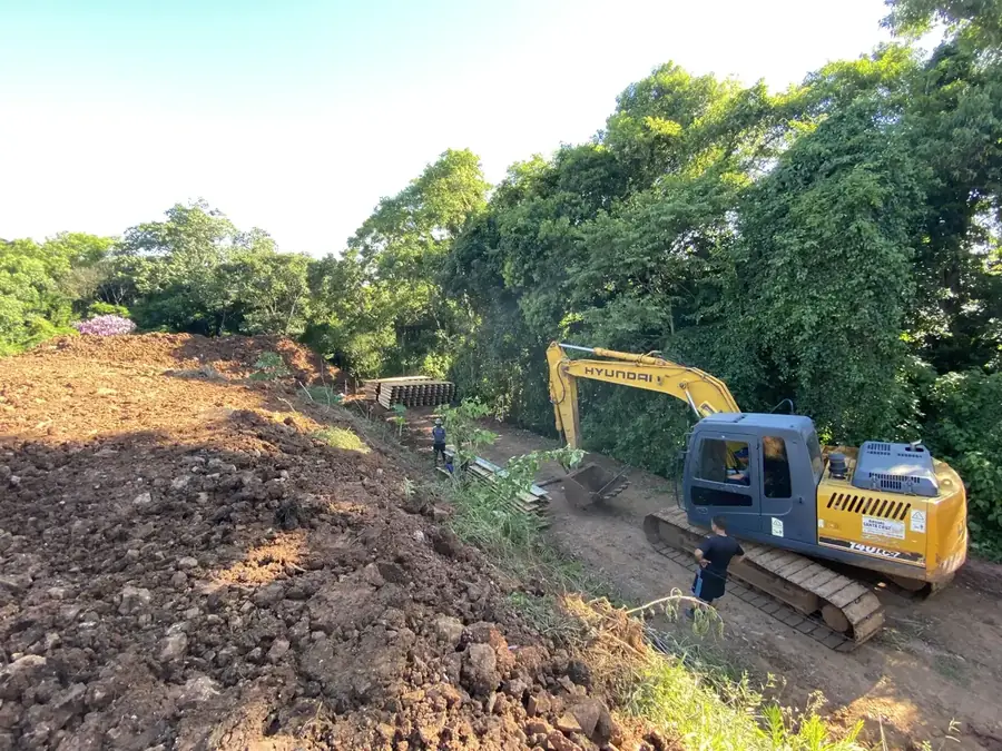 Escavadeira fazendo corte de terreno